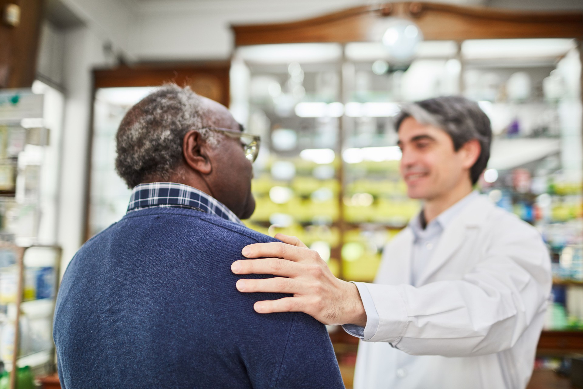 Smiling chemist consoling senior costumer at pharmacy